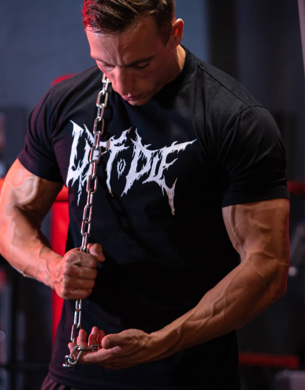 Atleta che regola la catena in acciaio rinforzato della cintura per sollevamento pesi professionale Warrior Gear.