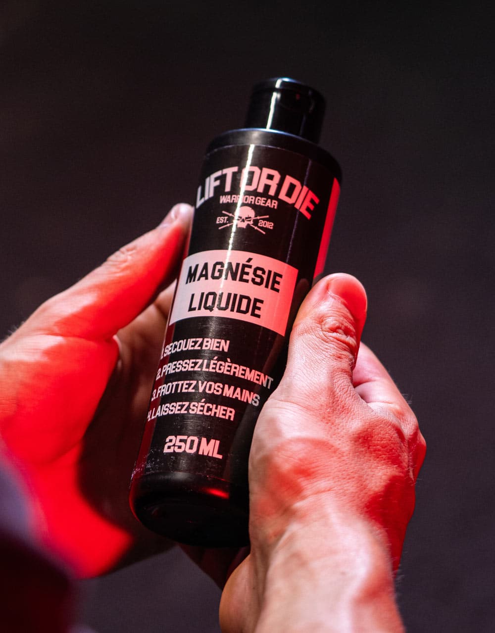 For photo 1 (Clean hands holding the bottle): Alternative text (Alt text): 250ml Warrior Gear liquid magnesium bottle held between two clean hands, showing instructions for use.
