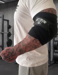 Bandes de coudes Lift or Die Warrior Gear portées pendant un entraînement de musculation, avec maintien du coude et poing fermé.