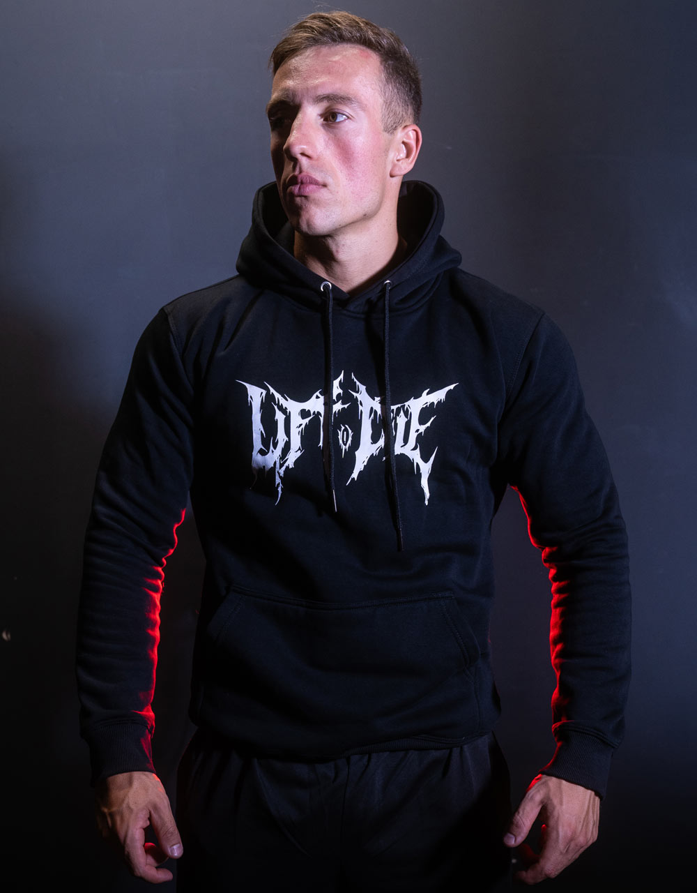 Athlète de face portant le sweat à capuche noir de musculation Warrior Gear avec poche kangourou et logo Lift or Die.