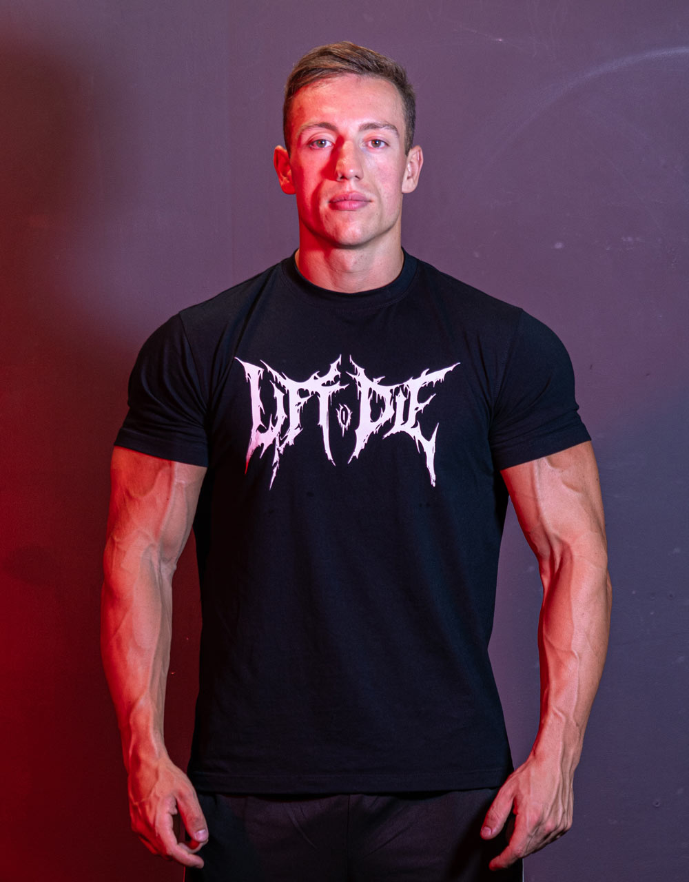 Athlete facing forward wearing the Warrior Gear fitted black bodybuilding t-shirt with Lift or Die Death Metallogo.